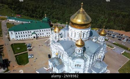 Luftaufnahme Einer weißen Kirche mit goldenen Kuppeln. Clip. Große, wunderschöne orthodoxe Kirche auf einem wolkigen Himmelshintergrund Stockfoto