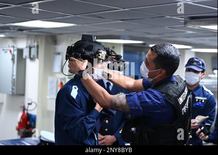 Während des mehrtägigen Hafens von Kimball in Kagoshima, Japan, am 13. Februar 2023 versuchen die Soldaten der japanischen Küstenwache bei einer Tour durch den Küstenwache Cutter Kimball (WMSL 756) die Ausrüstung der Strafverfolgungsbehörden anzuziehen. Kimballs Besatzung ist in Kagoshima, um gemeinsame Schulungen und einen professionellen Austausch mit Mitgliedern der japanischen Küstenwache durchzuführen und damit eine Kooperationsvereinbarung auszubauen, die 2022 zwischen den beiden Seeverkehrsdiensten unterzeichnet wurde und mit der die Operation SAPPHIRE, eine Daueroperation zur Stärkung der Beziehungen, zur Verstärkung bilateraler Engagements, eingeführt wurde; Und konzentrieren Sie sich auf die Aufrechterhaltung eines freien und offenen Indo-Pacific. USA Küsten-Gua Stockfoto