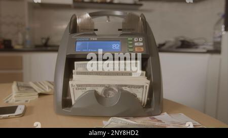 Der elektronische Geldautomat zählt die Dollarscheine. Filmmaterial. Automatische Geldzählung in der Maschine Stockfoto