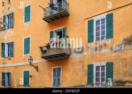 Fassade eines traditionellen mediterranen Hauses mit Trompe-l'oeil-Illusion auf Fenstern und Blumentöpfen auf einem Balkon in der Altstadt von Nizza, Frankreich Stockfoto