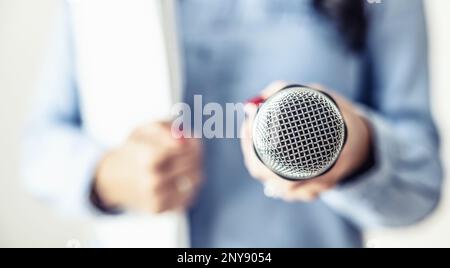 Journalistin auf einer Pressekonferenz mit Mikrofon und Notizbuch. Stockfoto