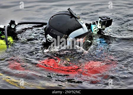 Ein Feuerwehrmann mit dem Tauchteam der Feuerwehr der Direktion Rettungsdienste praktiziert am 11. Januar 2023 ein Eisrettungsszenario an einem gefrorenen Big Sandy Lake an der South Post in Fort McCoy, Wisconsin. Mehrere Feuerwehrleute aus dem Team zogen einen Anzug an, schnallten sich einen Lufttank und eine Vollmaske an und tauchten in die Tiefen des Big Sandy Lake unter dem Eis an der South Post von Fort McCoy. Die Taucher bearbeiteten Tiefen von bis zu 15 Fuß oder mehr, um verschiedene Arten von Rettungsszenarien unter der Anleitung von anderen Feuerwehrleuten durchzuführen. Taucher wechselten sich ab und gingen in das Loch, das geschnitten wurde Stockfoto