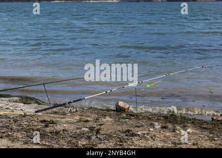 Angelruten und Angelausrüstung am Flussufer, Seeküste aus nächster Nähe. Stockfoto