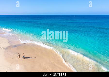 Aus der Vogelperspektive auf Touristen, Mutter und Sohn, die an einem abgeschiedenen wunderschönen Strand spazieren gehen, während sie einen Familienurlaub auf der Insel Sal, Cabo verde, Afrika machen Stockfoto