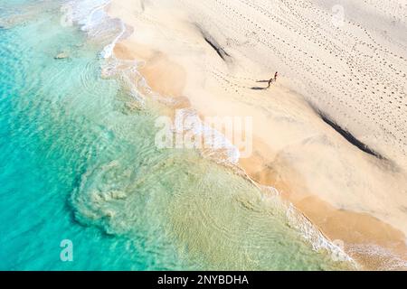 Aus der Vogelperspektive auf Touristen, Mutter und Sohn, die an einem abgeschiedenen wunderschönen Strand spazieren gehen, während sie einen Familienurlaub auf der Insel Sal, Cabo verde, Afrika machen Stockfoto