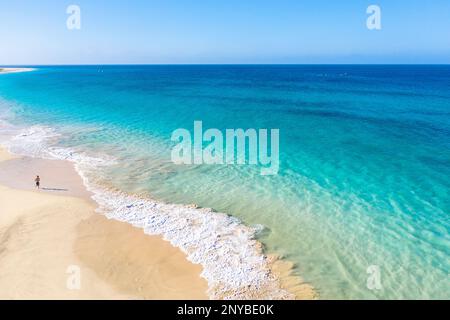 Aus der Vogelperspektive eines Touristen, eines Jungen, der an einem abgeschiedenen wunderschönen Strand läuft, während er einen Familienurlaub auf der Insel Sal, Cabo verde, Afrika macht Stockfoto