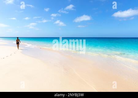 Frau in Badeanzug auf einem Urlaub, die an einem sonnigen Sommertag auf der Insel Sal, Cabo Verde, an einem idyllischen Sandstrand spaziert Stockfoto