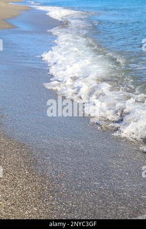 Kleine Wellen am Sandstrand Stockfoto