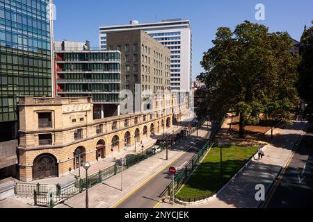 Bilbao, Spanien - 02. August 2022: Uribitarte-Straße mit der Fassade des alten Franco-Depots im Vordergrund, das Albia-Gebäude im Hintergrund Stockfoto