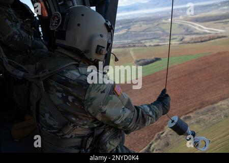 Sgt. 1. Klasse Jonas Chinea, ein Kosovo Force (KFOR) Regional Command-East (RC-E) Soldat mit der medizinischen Evakuierungseinheit der Charlie Company zugewiesen, 2. Bataillon, 149. Luftfahrtregiment, wartet auf seine Position, um eine Hebeoperation von einem UH-60 Black Hawk Helikopter in Camp Bondsteel, Kosovo am 6. Januar durchzuführen, 2023. Stockfoto