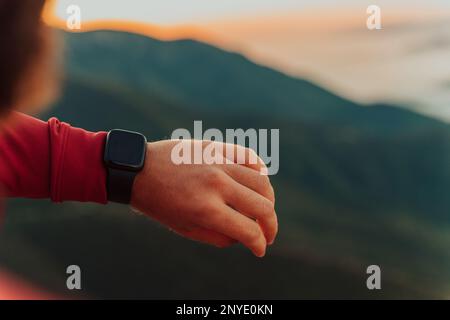 Mann, der während des Trainings Eine digitale Smartwatch verwendet. Nahaufnahme der Hände eines Mannes, der eine App in Smartwatch überprüft. Nahaufnahme Einer Uhr, die Schritte anzeigt Stockfoto