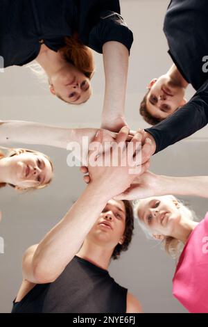 Ein Team von Leuten, die Händchen halten. Eine Gruppe glücklicher junger Frauen, die Händchen halten. Ansicht von unten, kleiner Winkel von Menschenhand. Freundschaft und Einheitskonzept Stockfoto