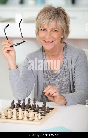 Glückliche Frau zu Hause, die allein Schach spielt Stockfoto