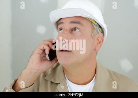 Builder am Telefon von einer Leiter Stockfoto