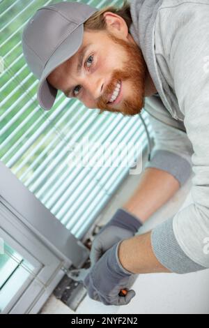Handyman passt das Fenster mit einer Zange an Stockfoto
