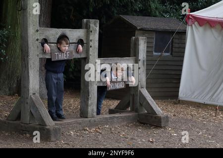 WARWICK. GROSSBRITANNIEN - 15. SEPTEMBER 2014: Nicht identifizierte Kinder spielen mit mittelalterlichen Aktien auf dem Unterhaltungsgelände von Warwick Castle. Stockfoto