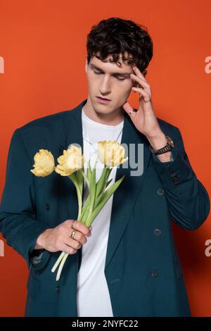 Trendiges Modell in Jacke mit Tulpen auf rotem Hintergrund, Stockbild Stockfoto