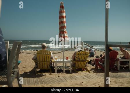 Gäste, die am Strand sitzen und an einem sonnigen Tag einen Cocktail genießen - St Kilda Beach, Victoria. Stockfoto