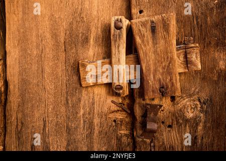 Antiker Schließmechanismus an historisch schäbigen Holztüren mit festgenagelten kleinen Häuserblocks in Mauretanien Stockfoto