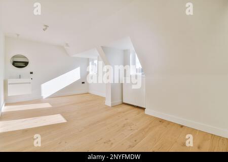 Innendesign eines hellen Dachzimmers mit weißen Wänden, Holzparkett und weißem Waschbecken mit Spiegel Stockfoto