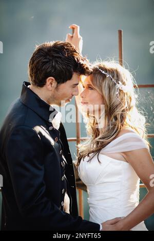 Attraktiver Mann in elegantem Anzug und hübsche Frau in Weiß Kleid lächelnd und Blick auf einander, während in der Nähe stehen Gealtertes Gebäude Stockfoto