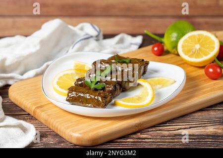 Olivenöl-Blattwicklung. Türkische Köstlichkeiten. Wickeln von Traubenblättern auf Holzhintergrund. Lokaler Name zeytinyaglı yaprak sarma oder dolma Stockfoto