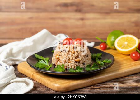 Mandelreis. Türkische Köstlichkeiten. Reis mit schwarzem Pfeffer, Zimt, Nelkenpfeffer, Johannisbeeren, Mandeln und Reis. Ramadan-Essen. Lokaler Name: Ic pila Stockfoto