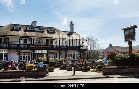 Ein geschäftiger Pub namens Pooley Bridge Inn, in dem Touristen draußen die Sonne im Pooley Bridge Ullswater Lake District, Cumbria, genießen Stockfoto