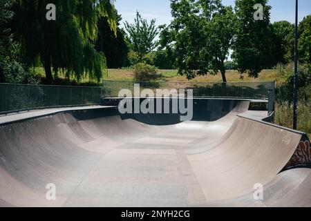 Eine horizontale Aufnahme eines leeren Skateparks im Sommer. Die Halfpipe oder der Pool sind draußen und kein Skateboard-Skater fährt dort. Stockfoto