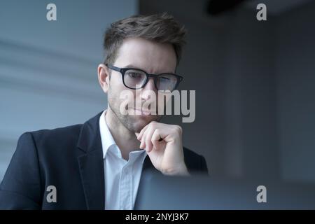 Fokussierter deutscher Mann Familie Anwalt in formeller Kleidung nachdenklich Blick auf Computer-Monitor, während entfernt arbeiten von modernen Home Office sorgfältig REA Stockfoto