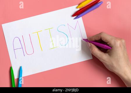 Textwort Autismus auf Papierbogen mit bunten Buchstaben auf blauem Hintergrund Stockfoto