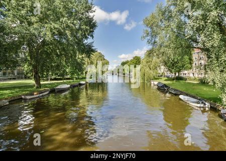 Amsterdam, Niederlande - 10. April 2021: Einige Boote auf dem Wasser in der Nähe von Bäumen und Gebäuden in amsterdam, niederlande Foto von Docht/Shutterstocker Stockfoto