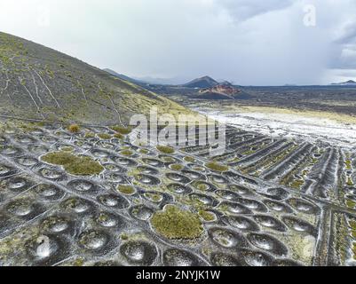 Luftaufnahme der Weinzucht auf vulkanischem Boden der Kanarischen Insel Lanzarot, mit Weinbau mit kleinen, salzbedeckten Regenwassergruben Stockfoto