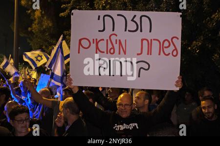 JERUSALEM, ISRAEL - MÄRZ 1: Amir Haskel, Der ehemalige General der Luftwaffe hält ein Schild mit der Aufschrift "Ich bin zurückgekehrt, um als Reservat auf der Straße zu dienen", während regierungsfeindliche Demonstranten israelische Flaggen und Parolen während einer Demonstration gegen Israels neuen Plan des Justizsystems in der Nähe des Privathauses von Ministerpräsident Benjamin Netanjahu am 1. März halten; In Jerusalem, Israel. Die Regierung Netanjahu treibt den Vorschlag einer Reform der Justiz voran, die die Fähigkeit des israelischen Obersten Gerichtshofs einschränken würde, Gesetze zu überprüfen und zu stürzen, die sie als verfassungswidrig erachtet. Kredit: Eddie Gerald Stockfoto