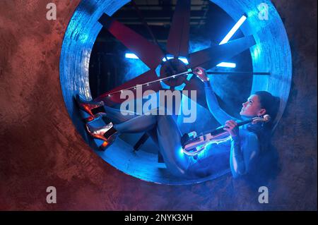 Violinist mit Gerät auf industrieller Luftgebläse-Turbine Stockfoto