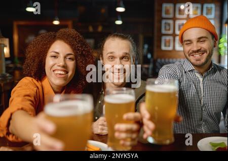 Eine Gruppe junger Leute, die vor der Kamera lächeln und mit Brille klappern Stockfoto