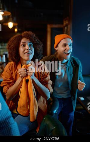 Eine Gruppe junger Freunde, die Fernsehen und ein Support-Team, während sie sich im Pub ausruhen Stockfoto
