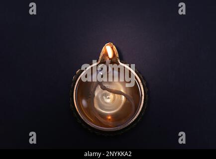 Beleuchtete Diya auf dunklem Hintergrund, Draufsicht. Diwali-Lampe Stockfoto