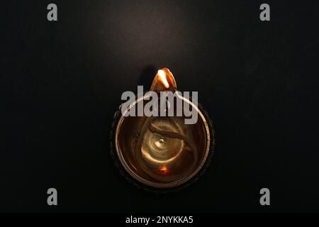 Beleuchtete Diya auf dunklem Hintergrund, Draufsicht. Diwali-Lampe Stockfoto