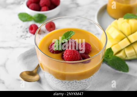 Köstlicher Chia-Pudding mit Mangosauce und Himbeeren auf dem Tisch, Nahaufnahme Stockfoto