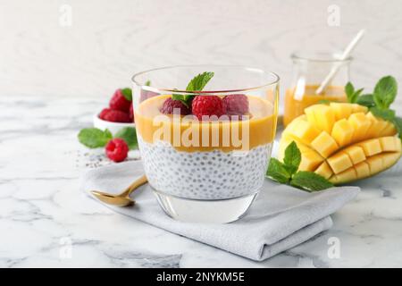Köstlicher Chia-Pudding mit Mangosauce und Himbeeren auf einem weißen Marmortisch Stockfoto