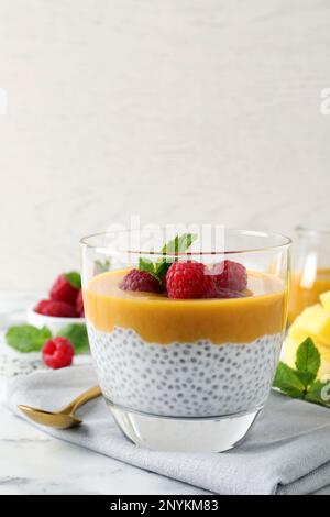 Köstlicher Chia-Pudding mit Mangosauce und Himbeeren auf einem weißen Marmortisch Stockfoto