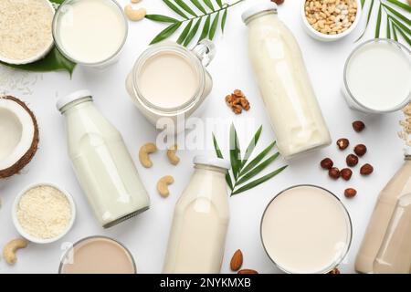 Verschiedene vegane Milch und Zutaten auf weißem Hintergrund, flach liegend Stockfoto