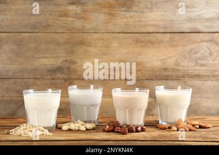 Verschiedene vegane Milch und Zutaten auf Holztisch. Platz für Text Stockfoto