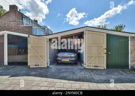 Eine Garage mit einem Auto, das in der Tür geparkt ist, und zwei Türen, die auf beiden Seiten der Garage offen sind, sind Backsteinwände Stockfoto