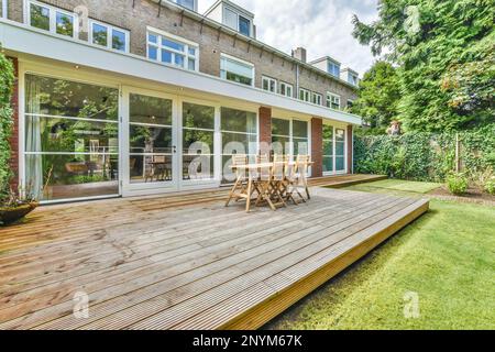 Eine Außenterrasse mit Holzterrasse und Glasschiebetüren, die in den hinteren Garten dieses Hotels im Westen londons führen Stockfoto