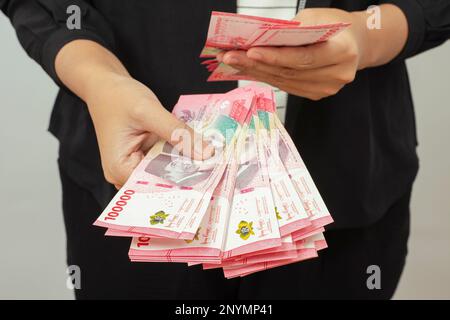 Konzept der Barzahlung. Indonesische Rupiah-Währung (Rp. 100,000 Seratus Ribu Rupiah), einhunderttausend indonesische Rupiah-Geld. Stockfoto