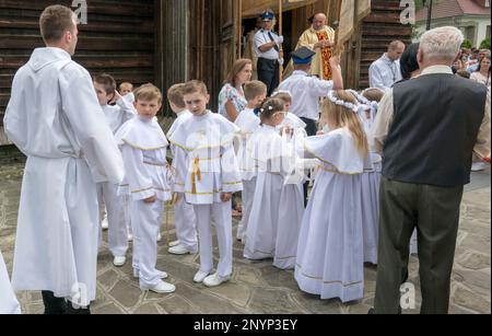 Junge Jungen und Mädchen in Erstkommunion-Kleidung, Priester in der Dorfkirche, Corpus Christi-Feier in Letownia, Gorals (polnische Highlander) Dorf, Beskiden Gebirgskette, Westkarpaten, Malopolska Region, Polen Stockfoto