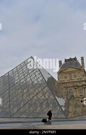 Unbekannte Straßenverkäufer von Reproduktionen des Eiffelturms selbst vor der Hauptpyramide des Louvre-Museums Stockfoto