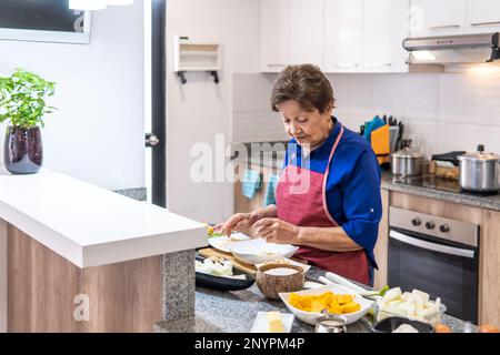 Oma bereitet Essen in der Küche zu Stockfoto